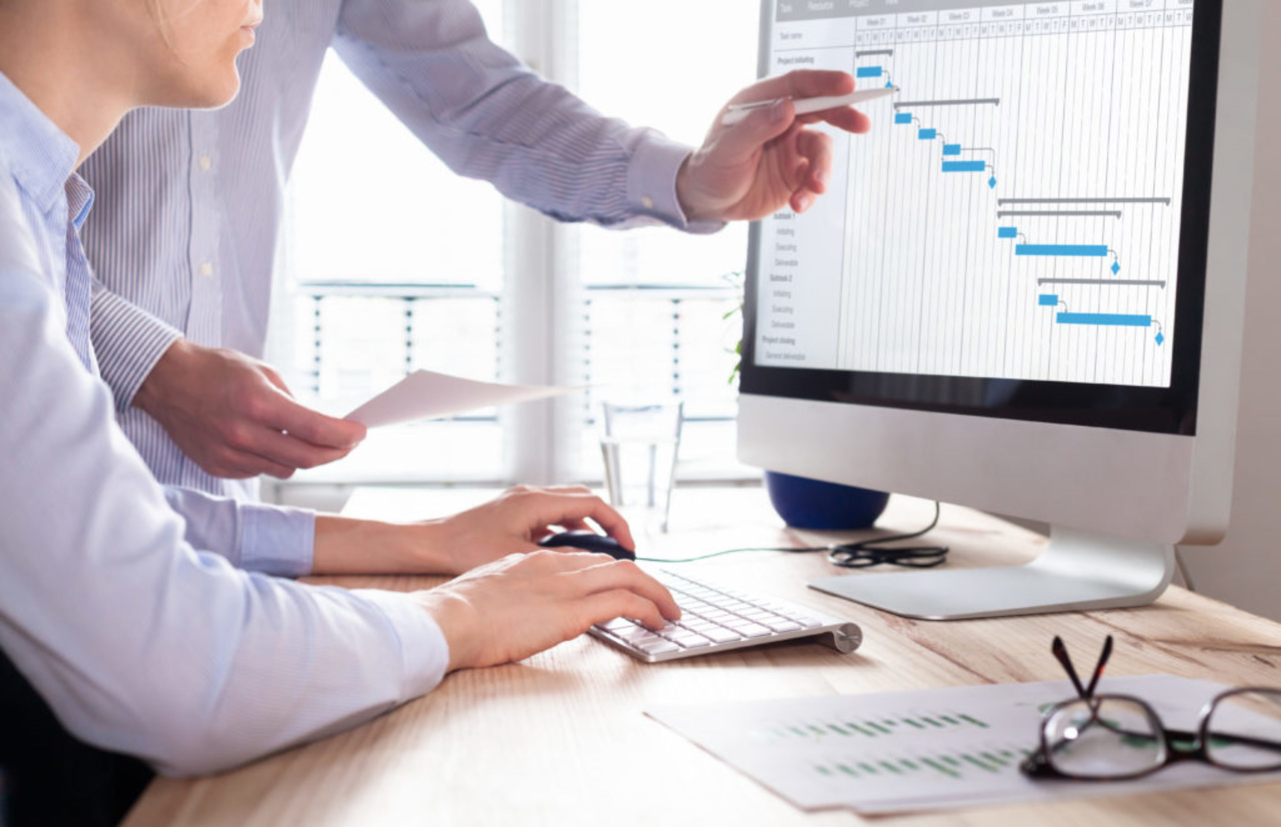 Project management team updating schedule or planning on computer, business